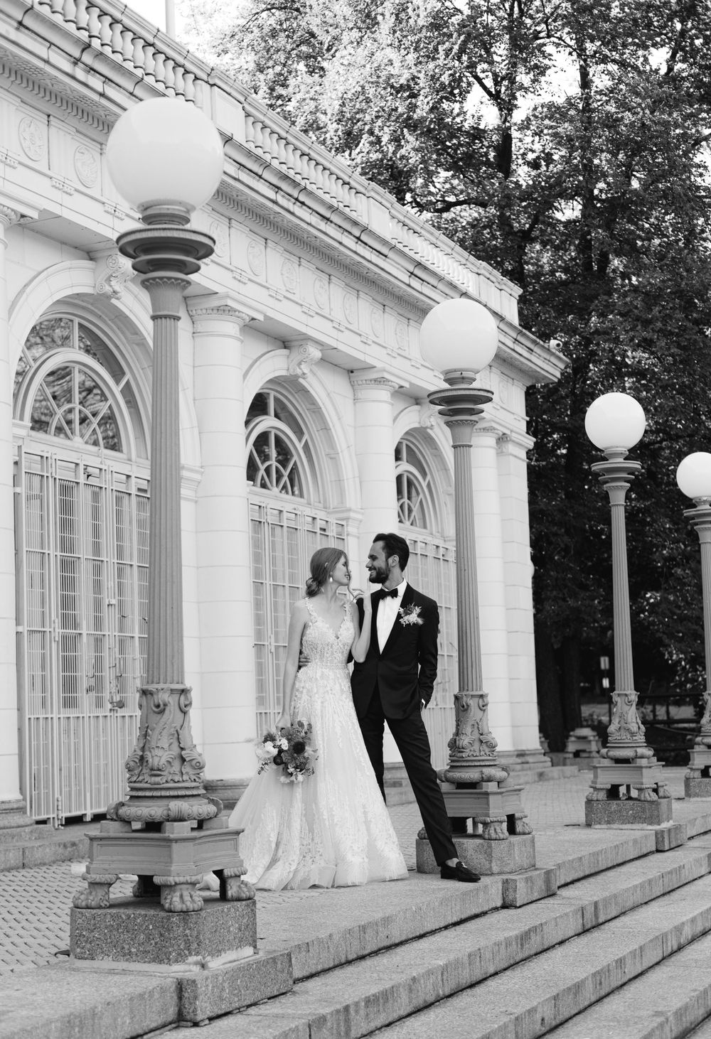 A classic black and white wedding photo on grand steps of a historic building.