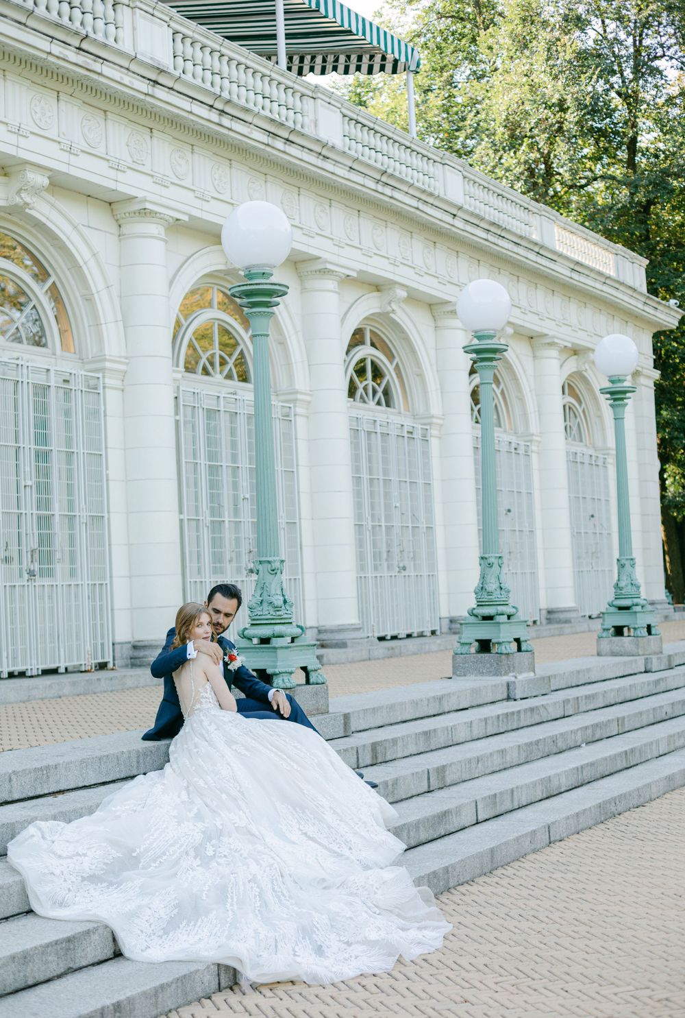 A wedding couple poses dramatically on stone steps of a classical building.