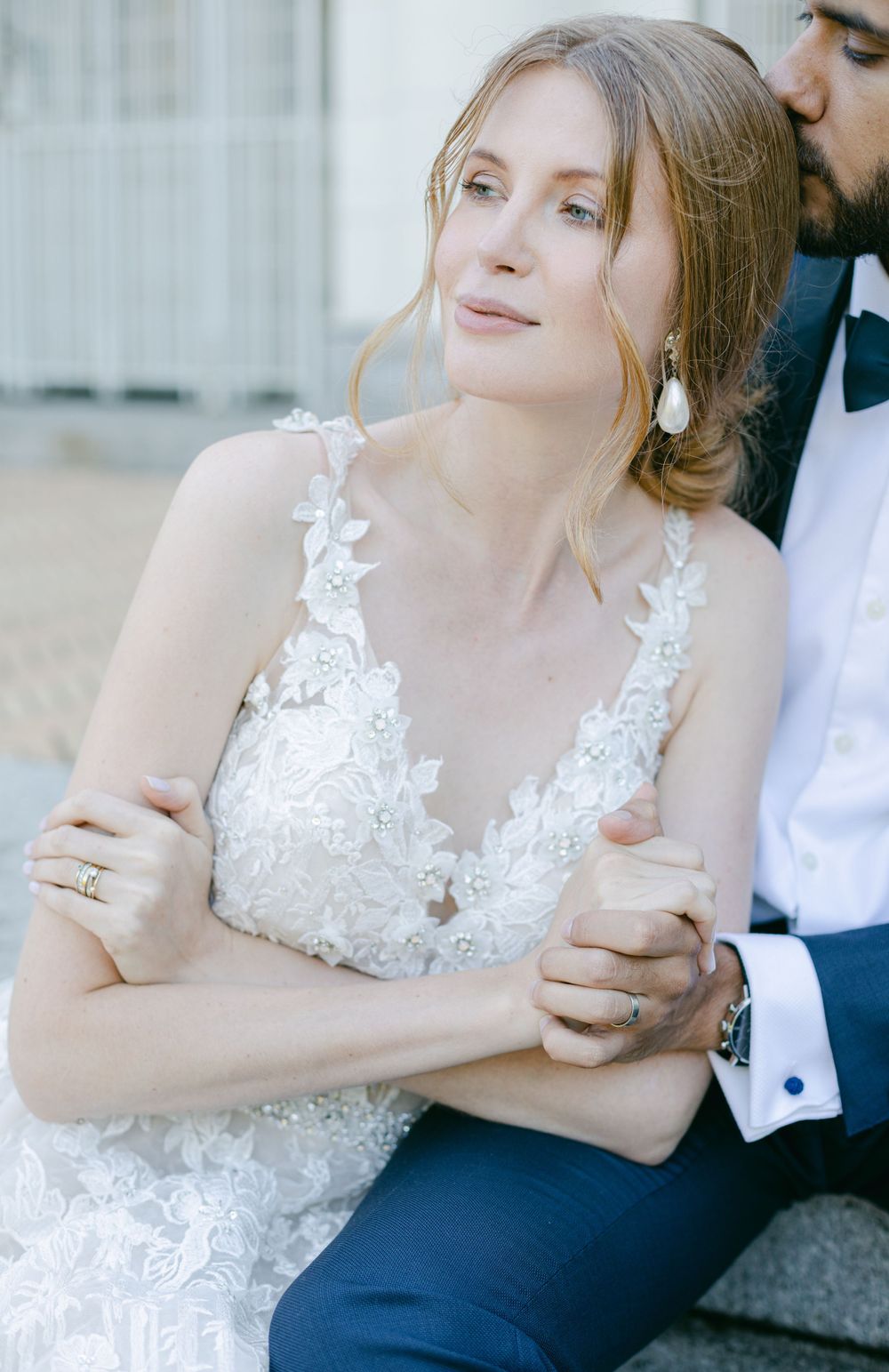 Elegant bridal portrait featuring intricate lace wedding gown and pearl drop earrings.