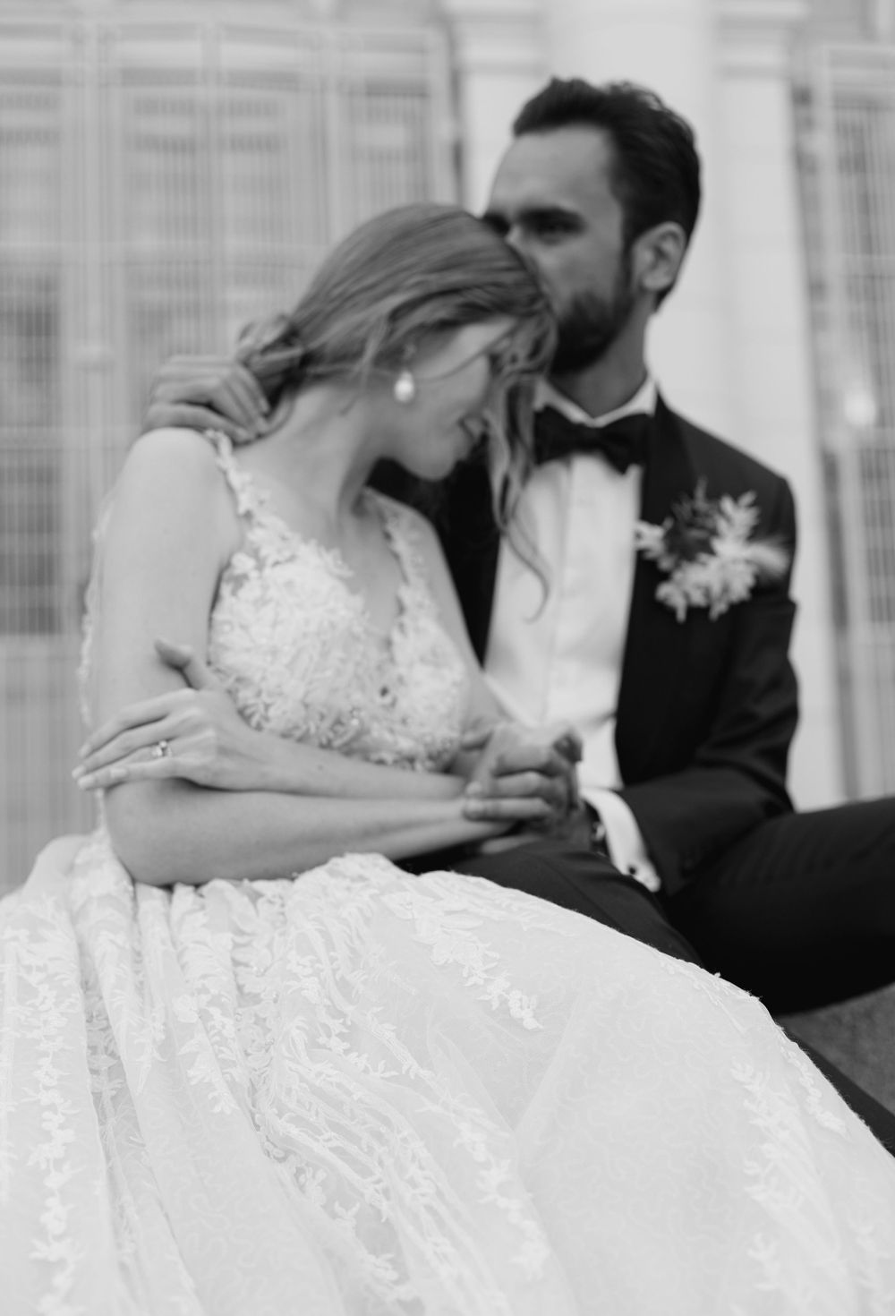 Black and white intimate wedding portrait capturing tender moment between newlyweds.