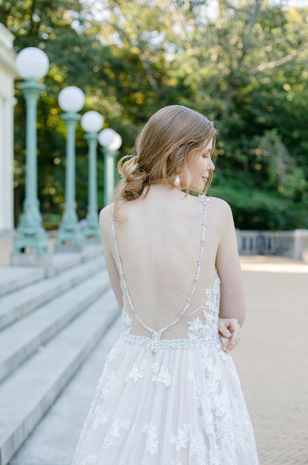 Detailed back view of sheer wedding gown showing delicate lace appliques and buttons.