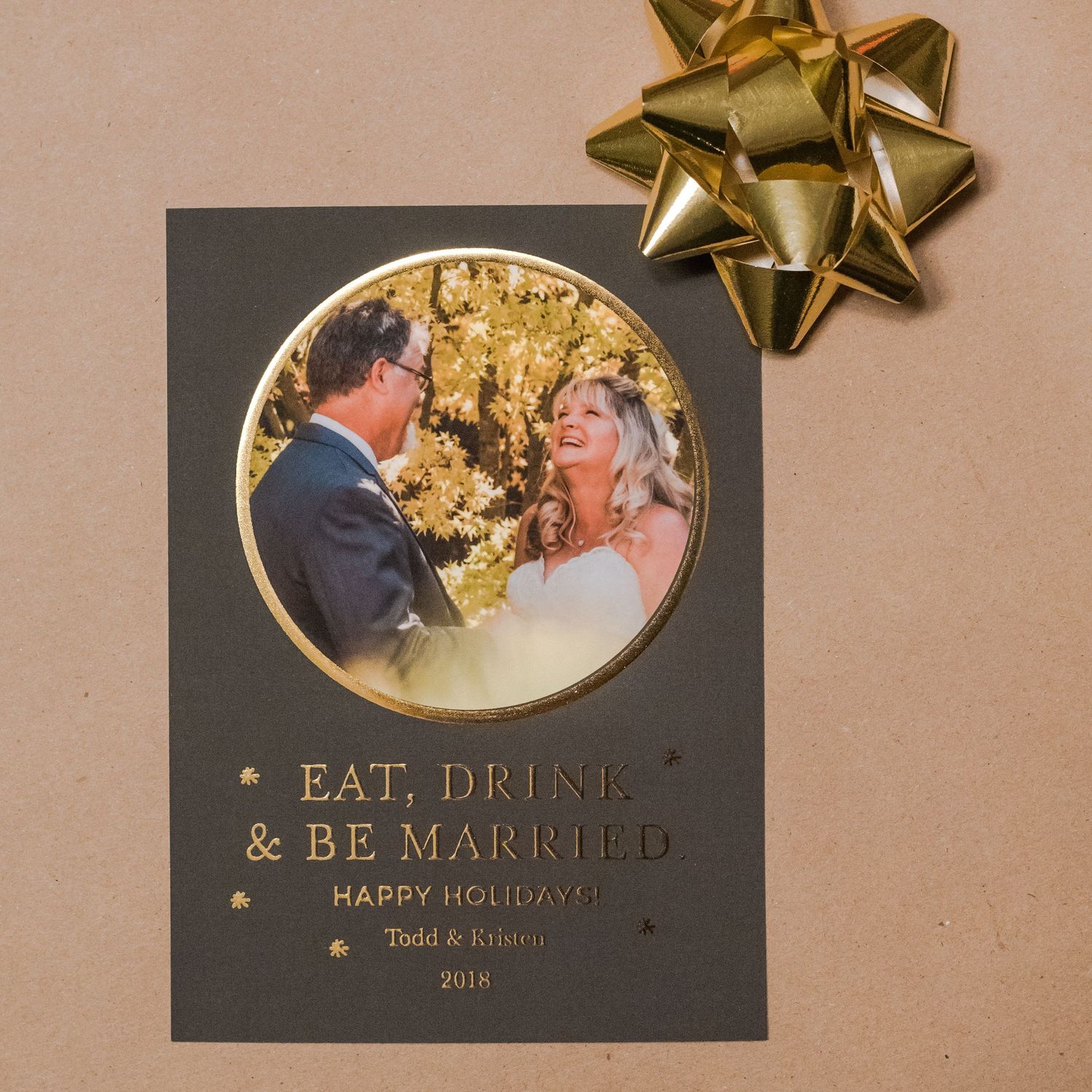 Wedding announcement card with gold accents featuring a circular photo of newlyweds against a dark background.