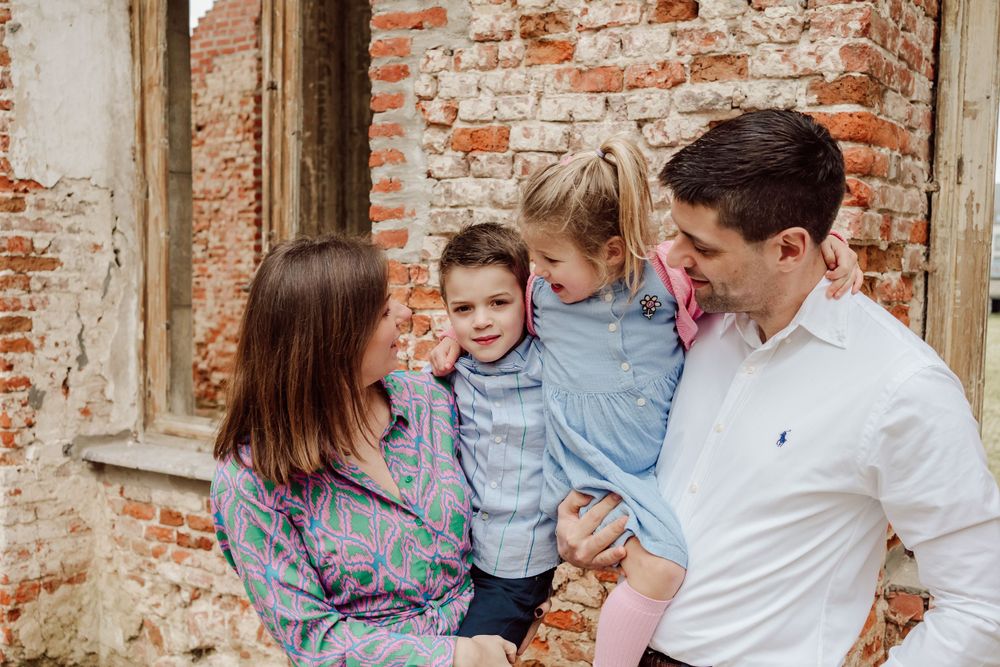 gezin tijdens communie zoon voor gevel vervallen pand
