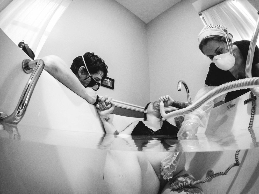 Black and white fisheye photo of water birth in tub with medical support.