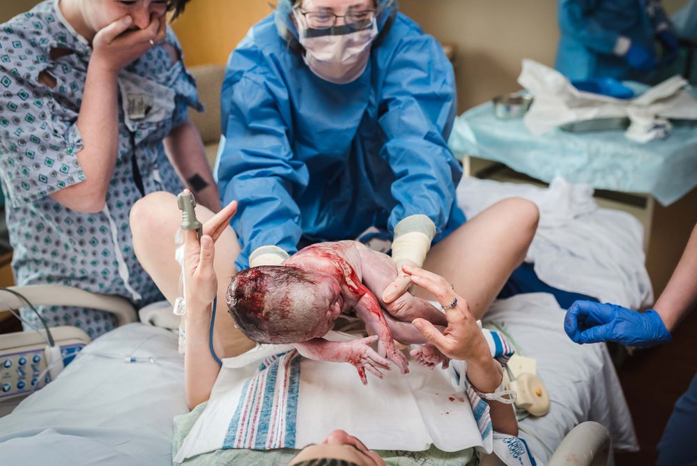 Medical team assisting mother during hospital delivery as newborn baby is born.