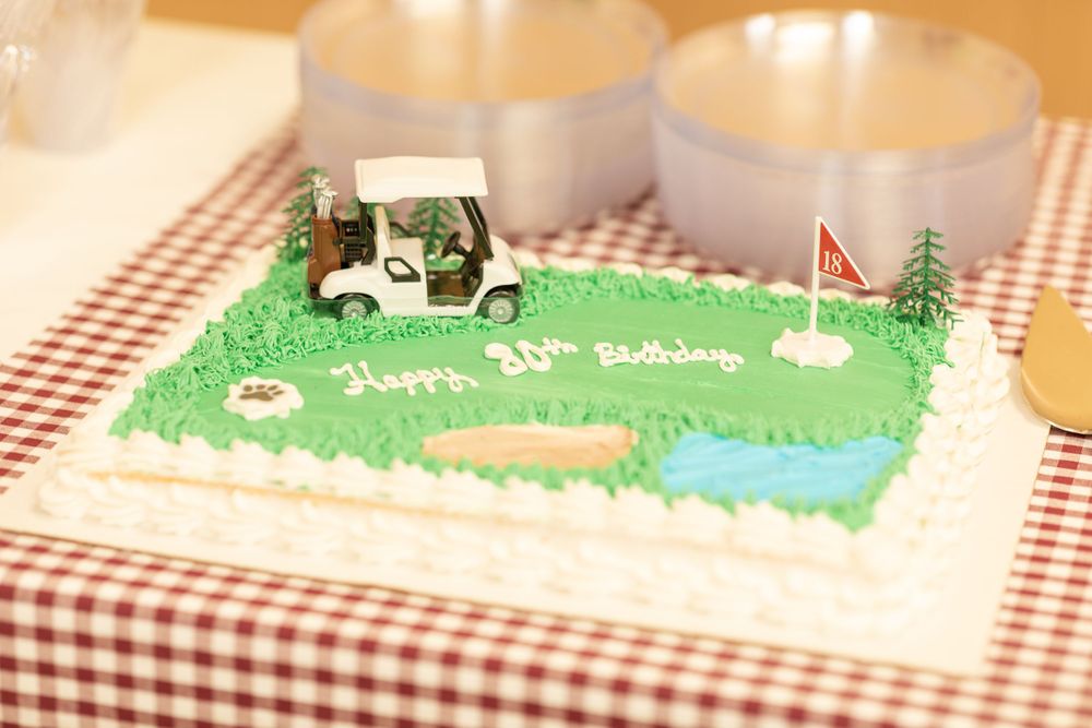 Golf-themed cake display with green frosting and miniature golf course decorations.