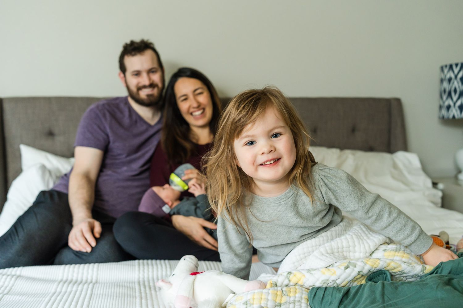 Parents playing on the bed with their toddler and newborn at home in Redmond.