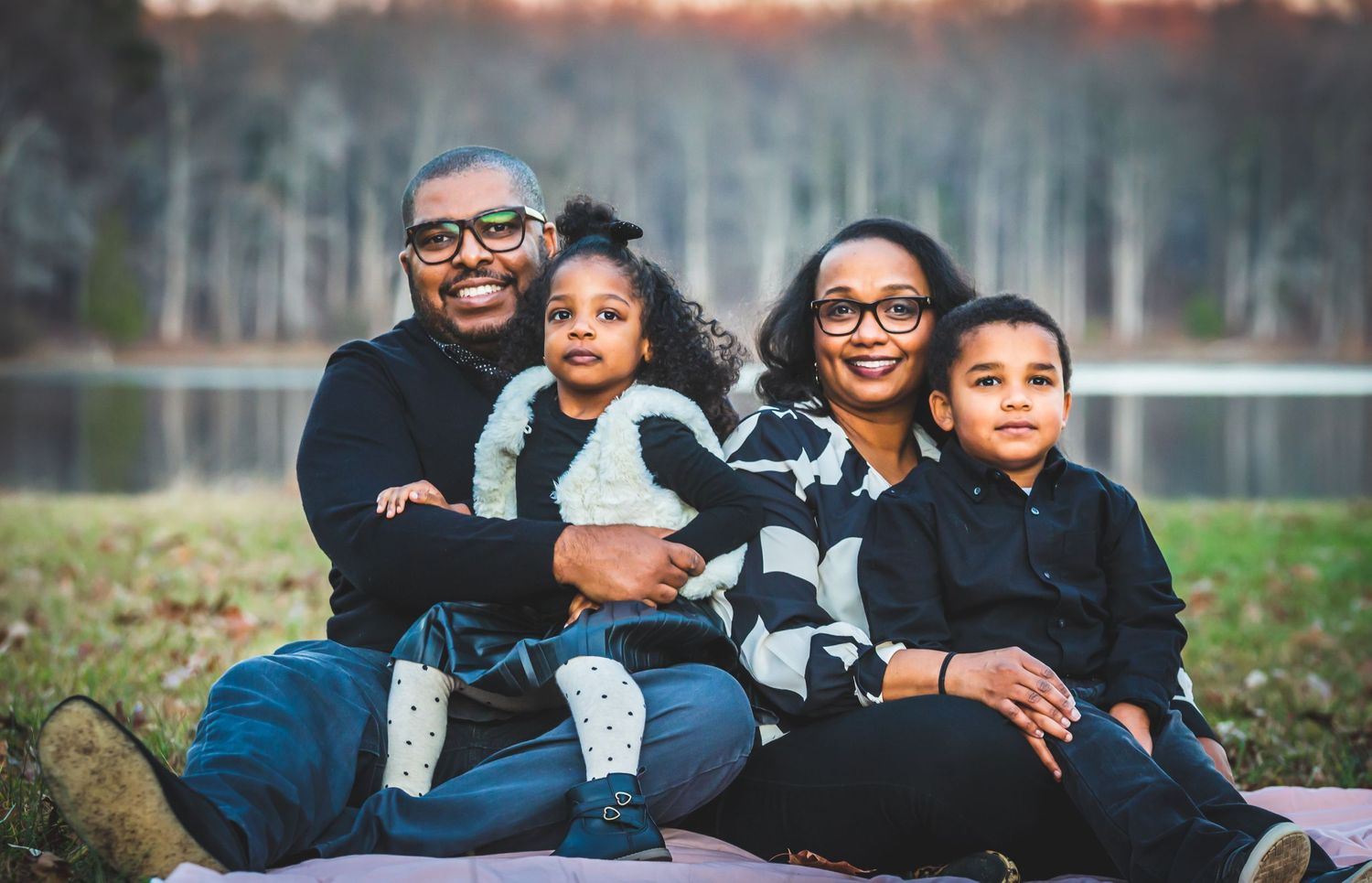 father, mother and two kids Smiling on grass