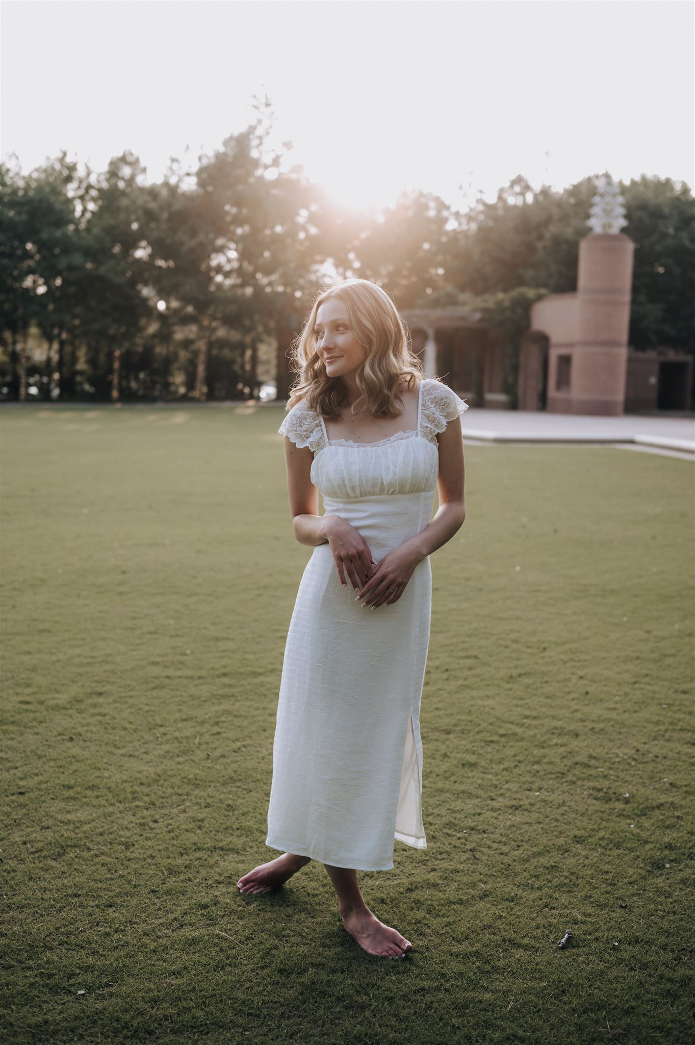 Ethereal sunset portrait in white summer dress on grass lawn.