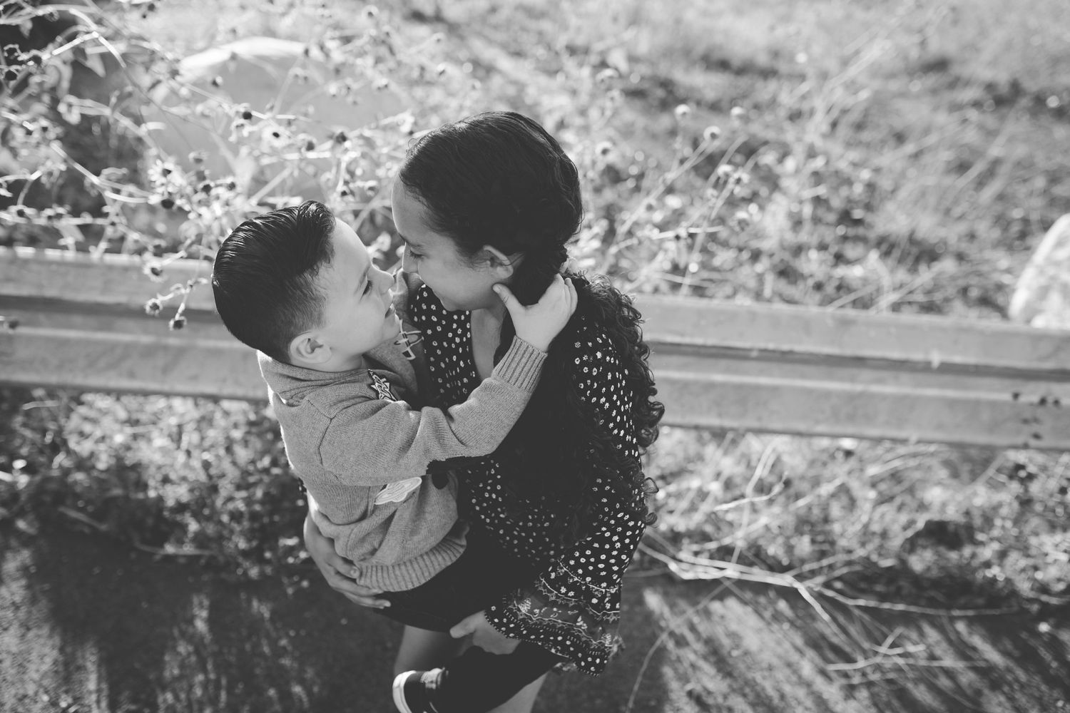 A sweet black and white portrait capturing an affectionate embrace outdoors.