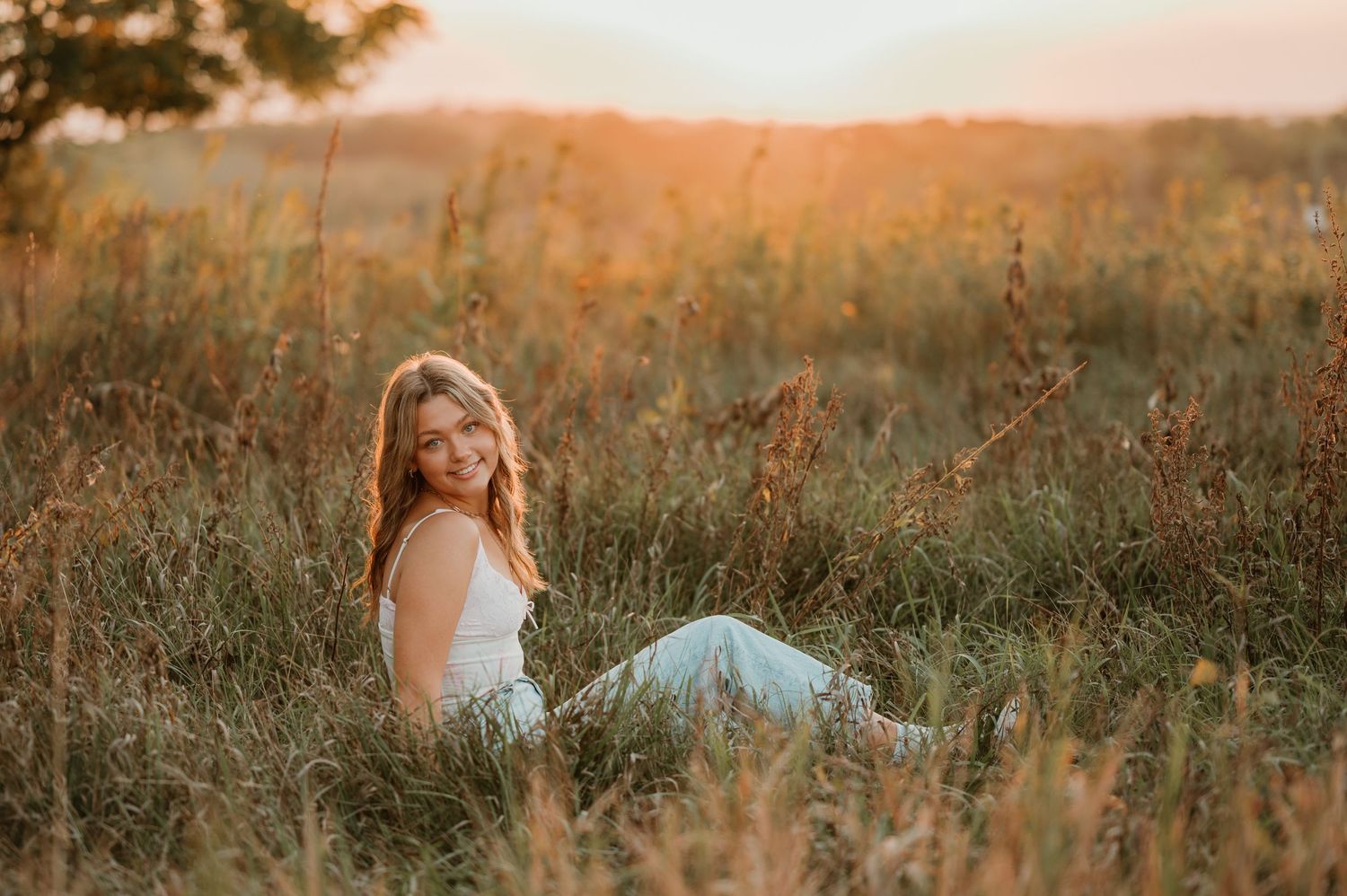 Sunset portrait session in tall grass field with warm golden lighting.