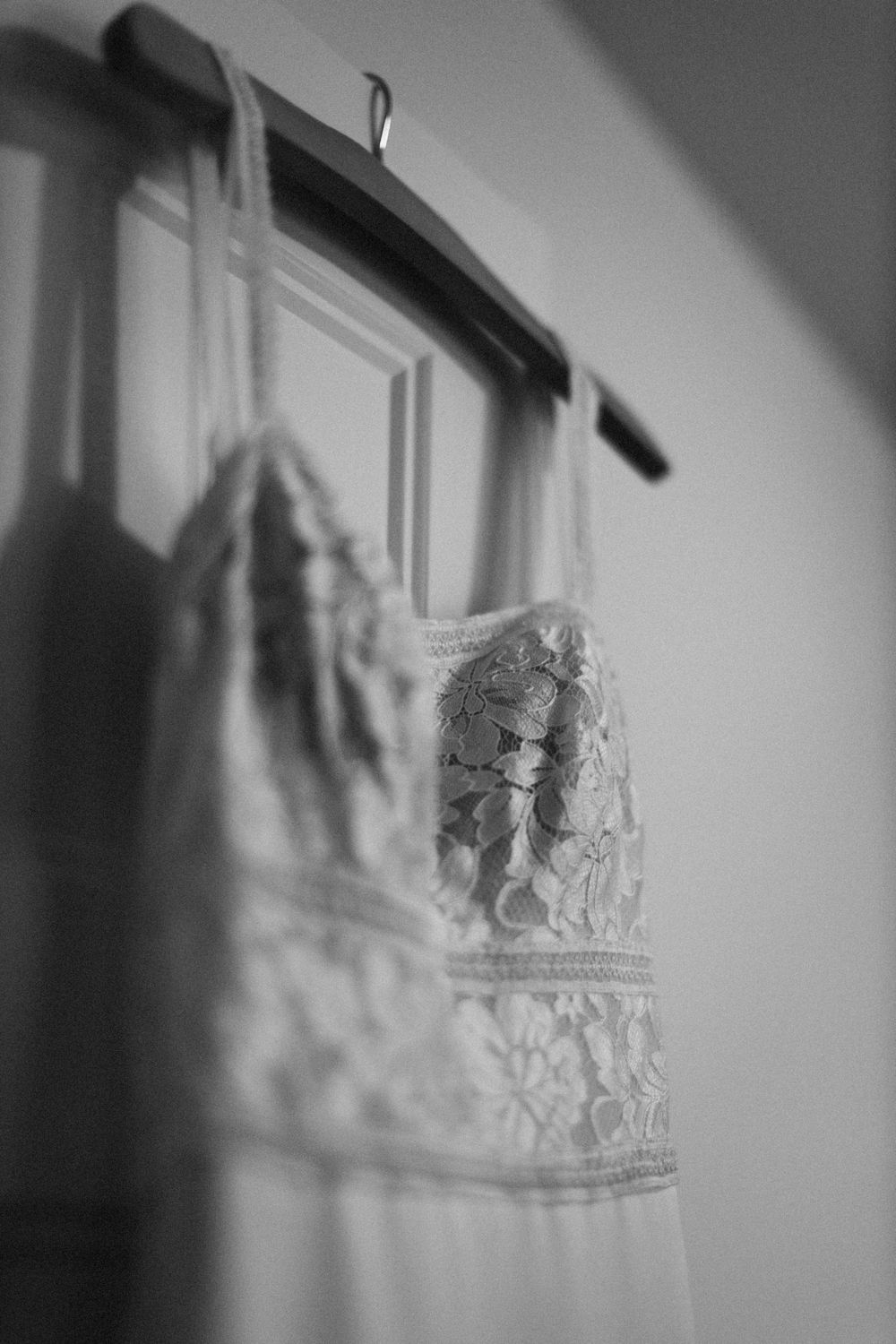 Black and white detail shot of a hanging lace wedding dress.
