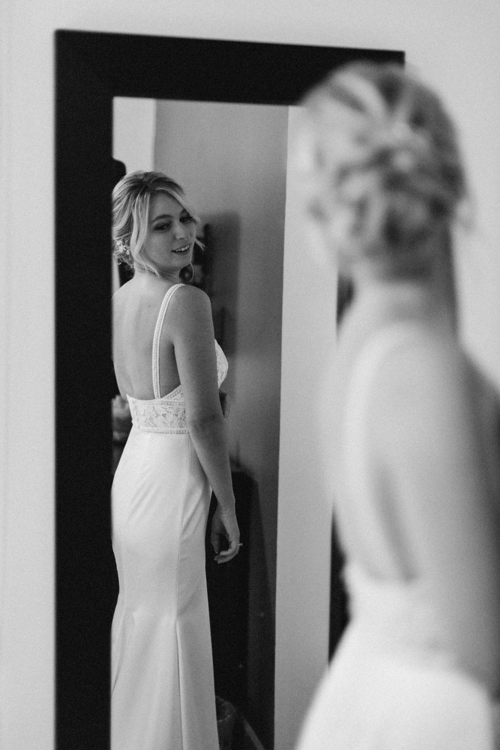 A bridal mirror reflection shows an elegant white dress with lace details.