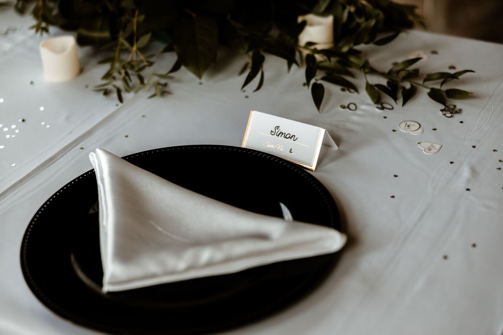 Minimalist wedding place setting with black charger plate and white napkin.