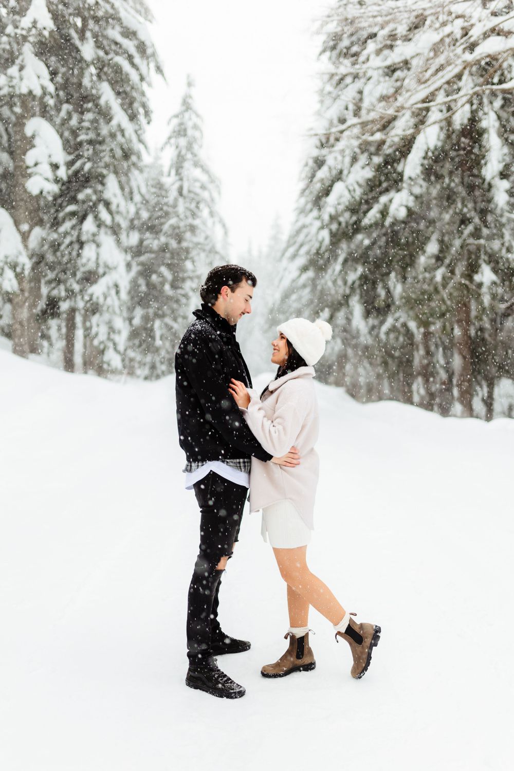 Couple sharing intimate moment in snow-covered forest setting.
