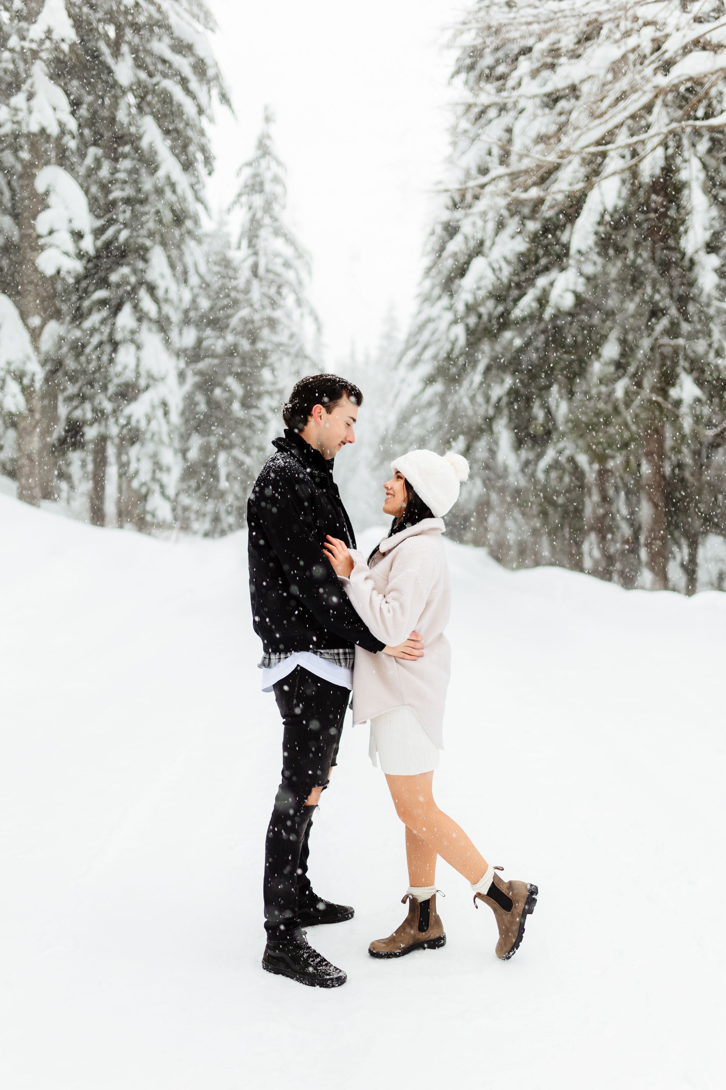 Couple sharing intimate moment in snow-covered forest setting.