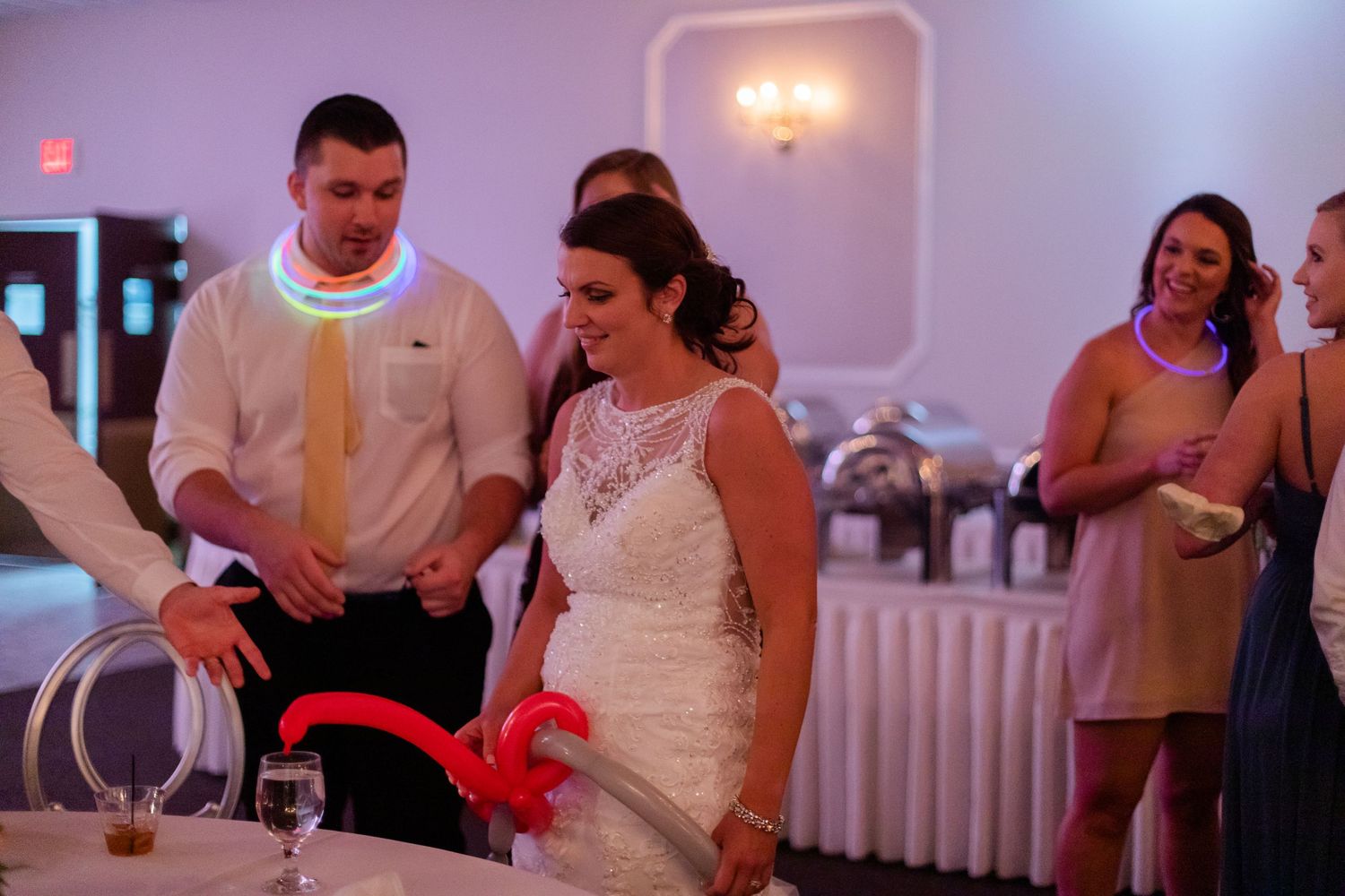 Wedding reception guests dancing and celebrating in a brightly lit venue.