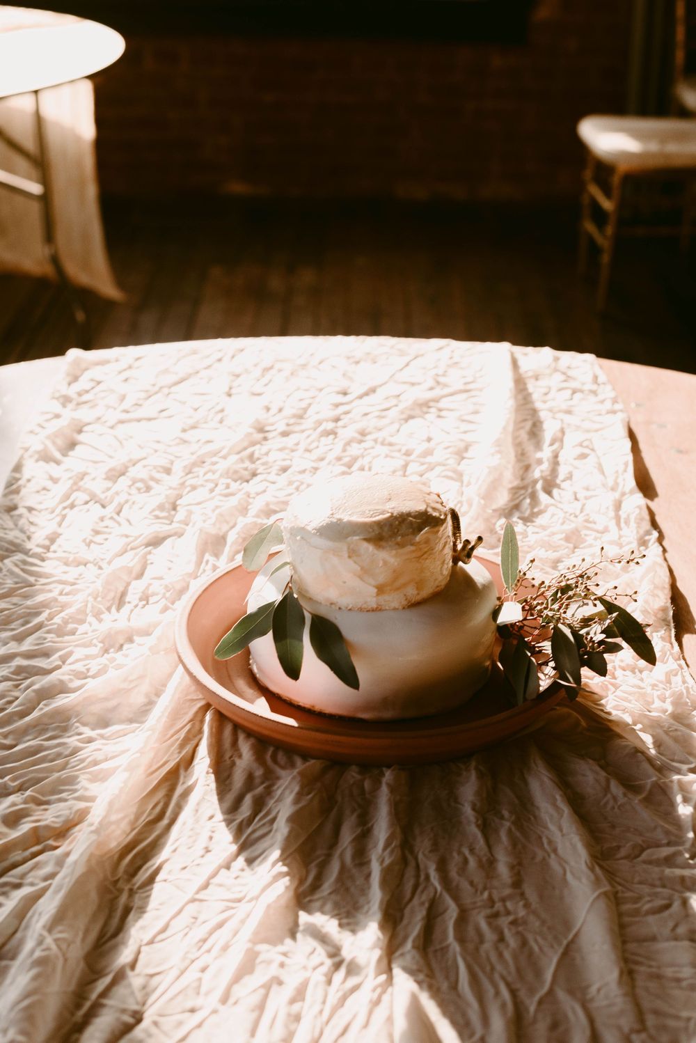 White teacup with floral arrangement on textured linen tablecloth in soft lighting.