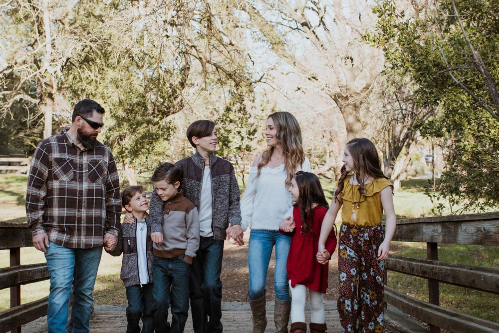 Group walking together on wooden bridge path surrounded by trees.