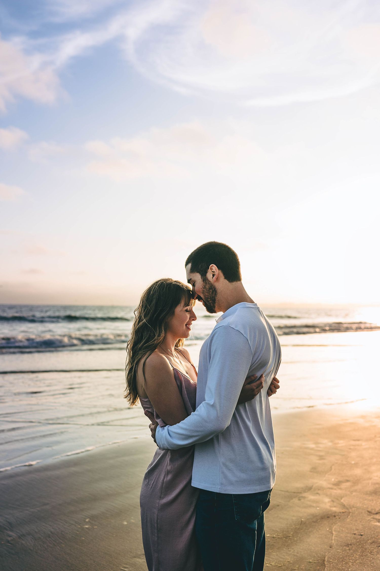 Intimate couple's portrait at sunset on golden sandy beach.