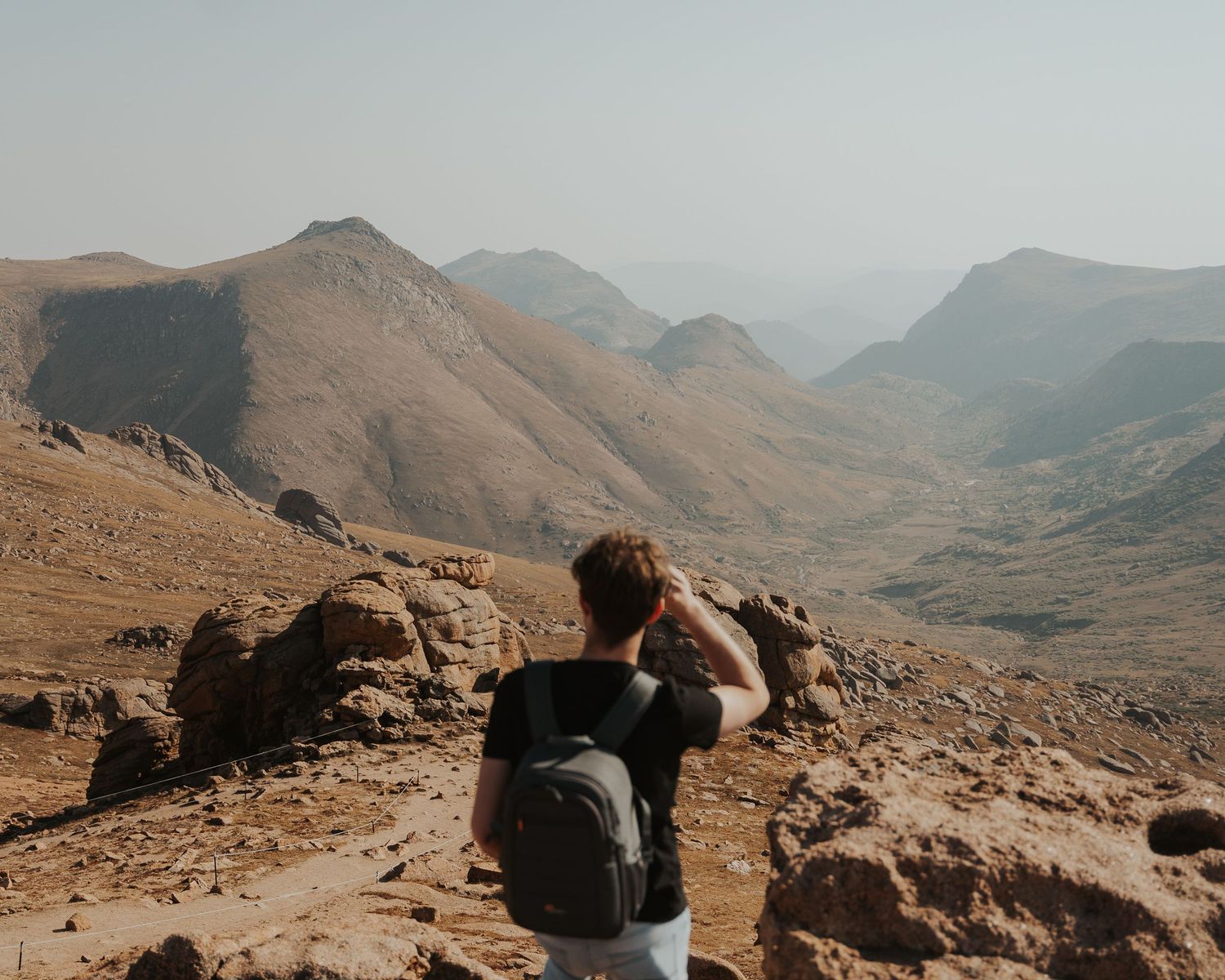 focus of photo is the mountain valley where a person is viewing out