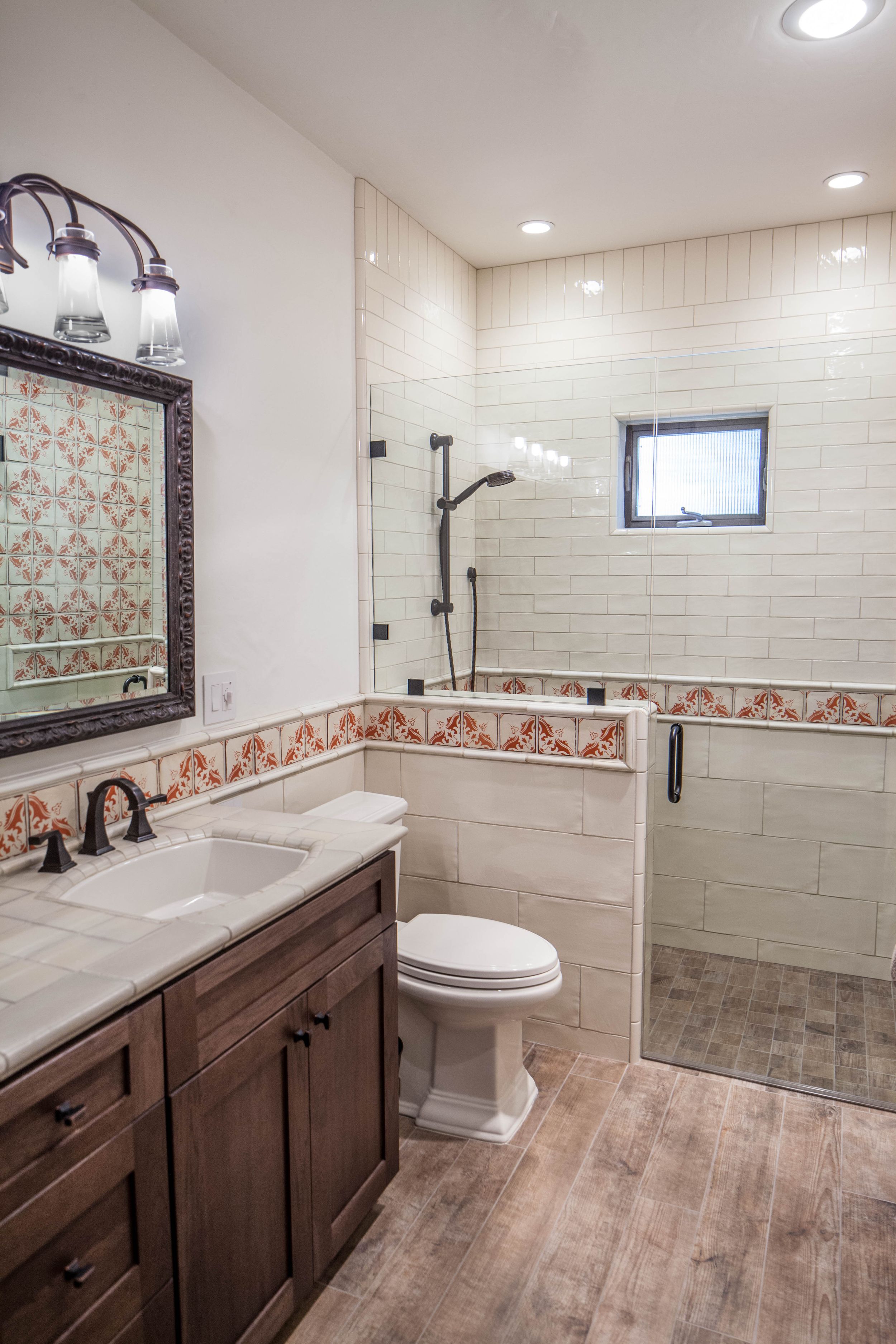 Elegant bathroom with decorative tile border, glass shower and wood vanity.