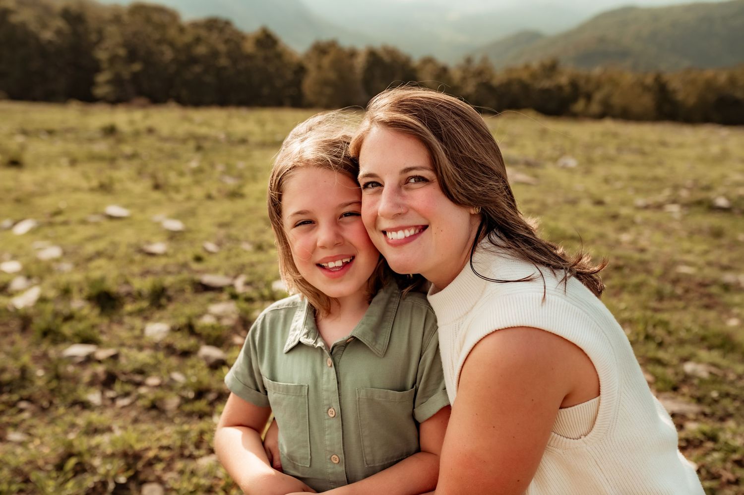 Mother and daughter embrace and look at camera during family photography session.