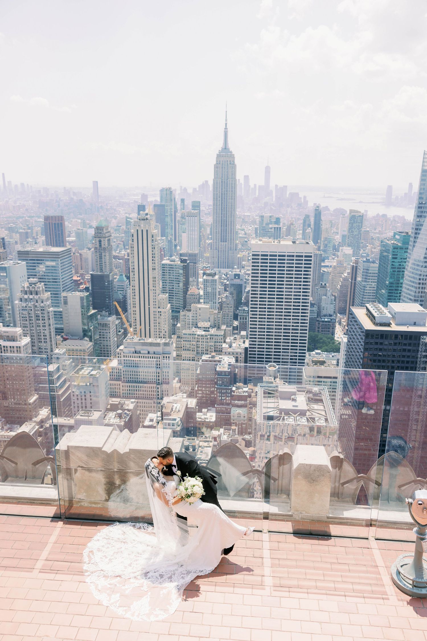 Romantic wedding moment on rooftop overlooking New York City skyline with Empire State Building.