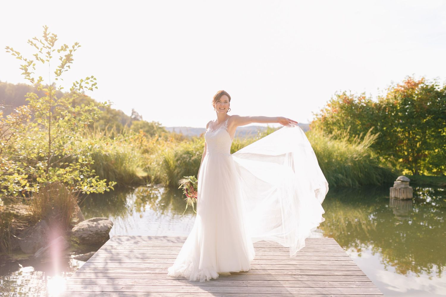 Hochzeitsfotografie - Braut im weißen Kleid tanzt auf Steg am Teich - Hofgut Hohenstein Lautertal