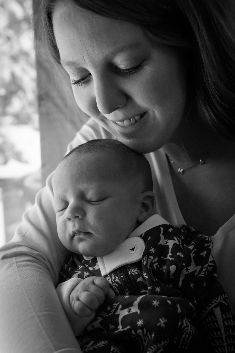A tender black and white portrait of a parent cradling their sleeping newborn.