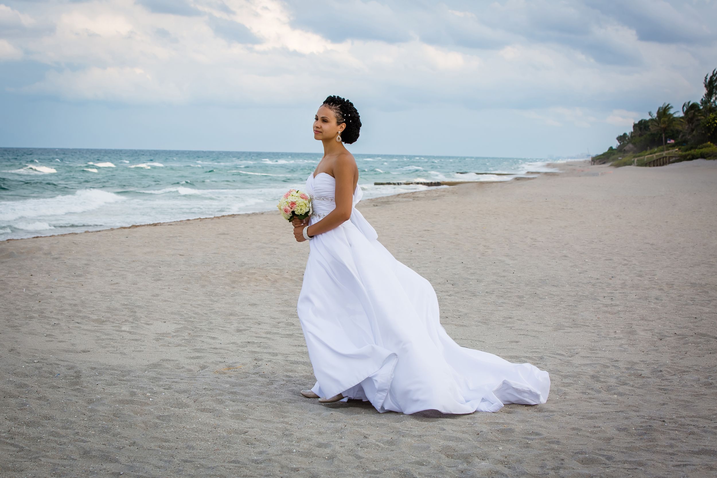 Romantic beach bridal photos with white dress flowing in the ocean breeze.