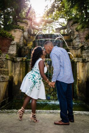 Playful engagement photo sequence in front of a stone fountain with water features.