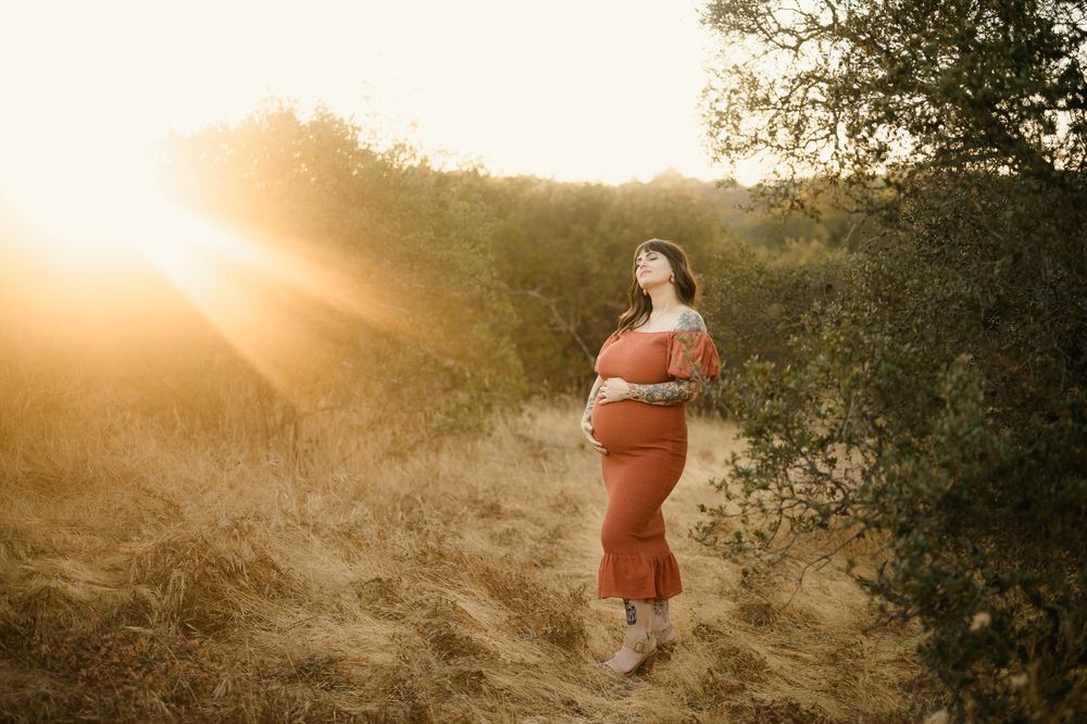 Maternity portrait by Camarillo maternity photographer of pregnant woman holding belly in the sunshine in grassy field