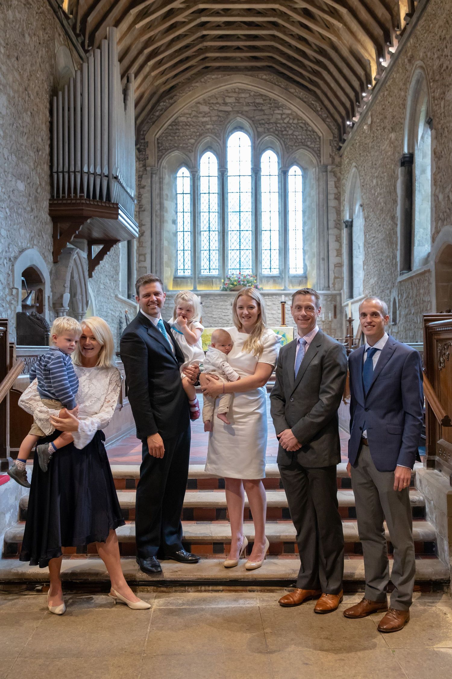 Extended family gathering on church steps with beautiful vaulted ceiling and organ pipes visible.