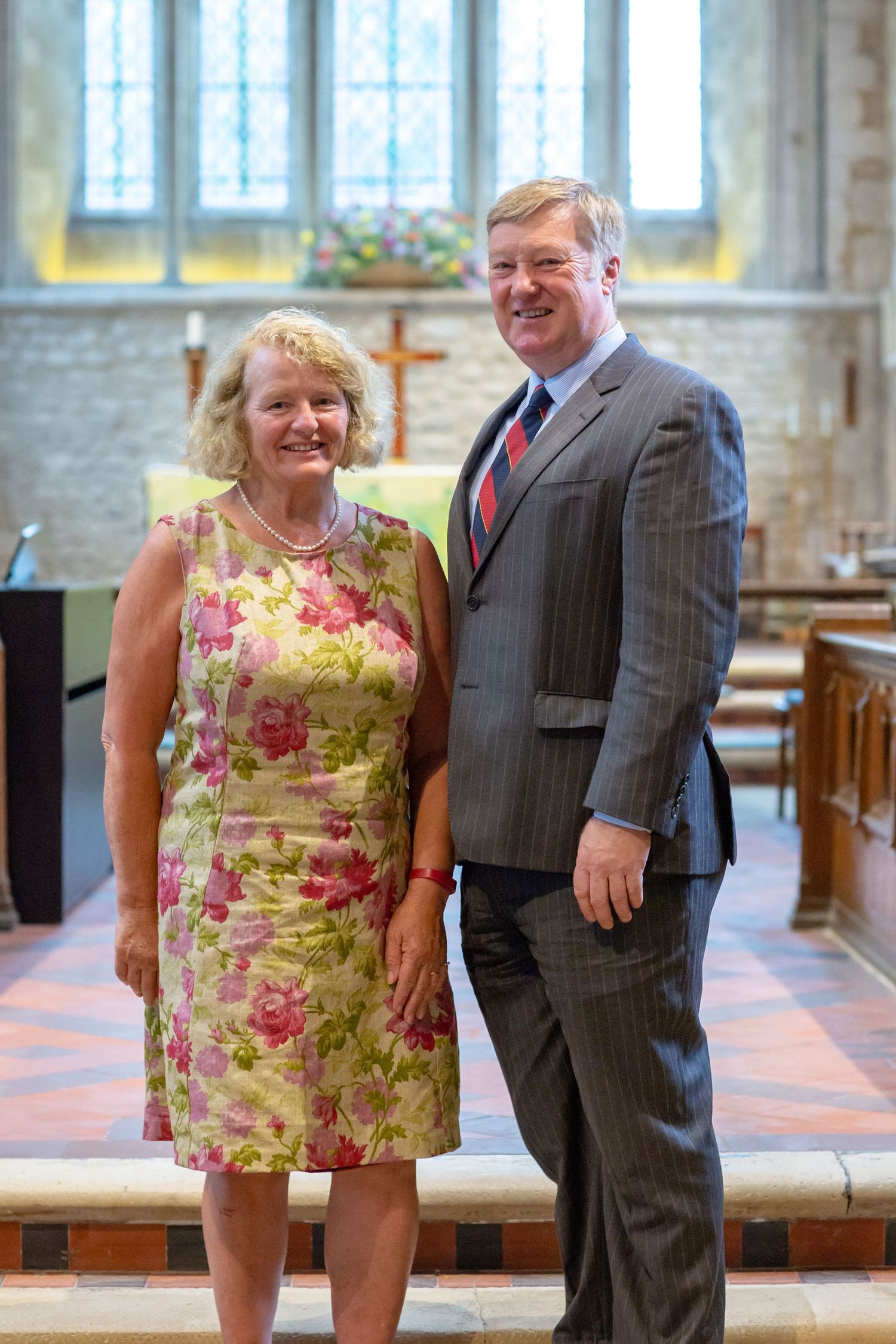 Couple standing together inside a church with stained glass windows and stone architecture.