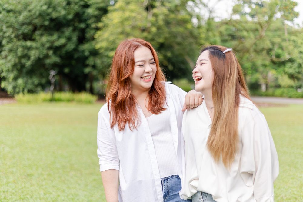 sisters dressed in white smiling happily in a green field
