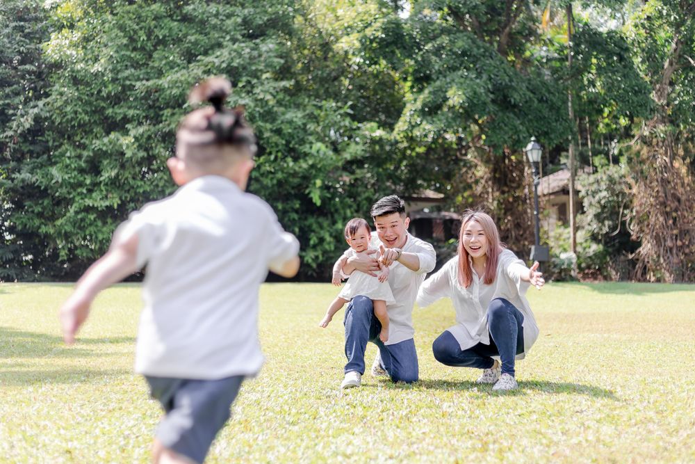 young boy running towards happy parents on a green field. family photoshoot