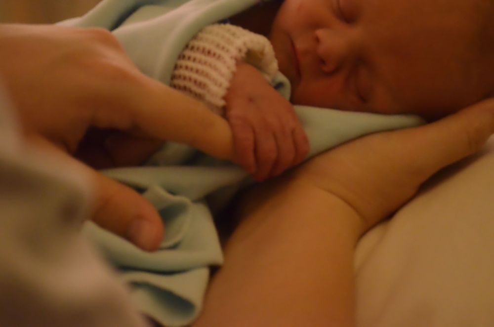 Blurred image of sleeping baby wrapped in light blue blanket.