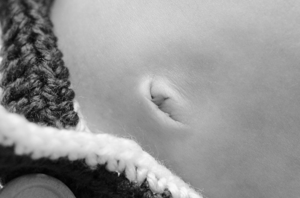 Close-up black and white photo of a small belly button with knitted fabric edge.