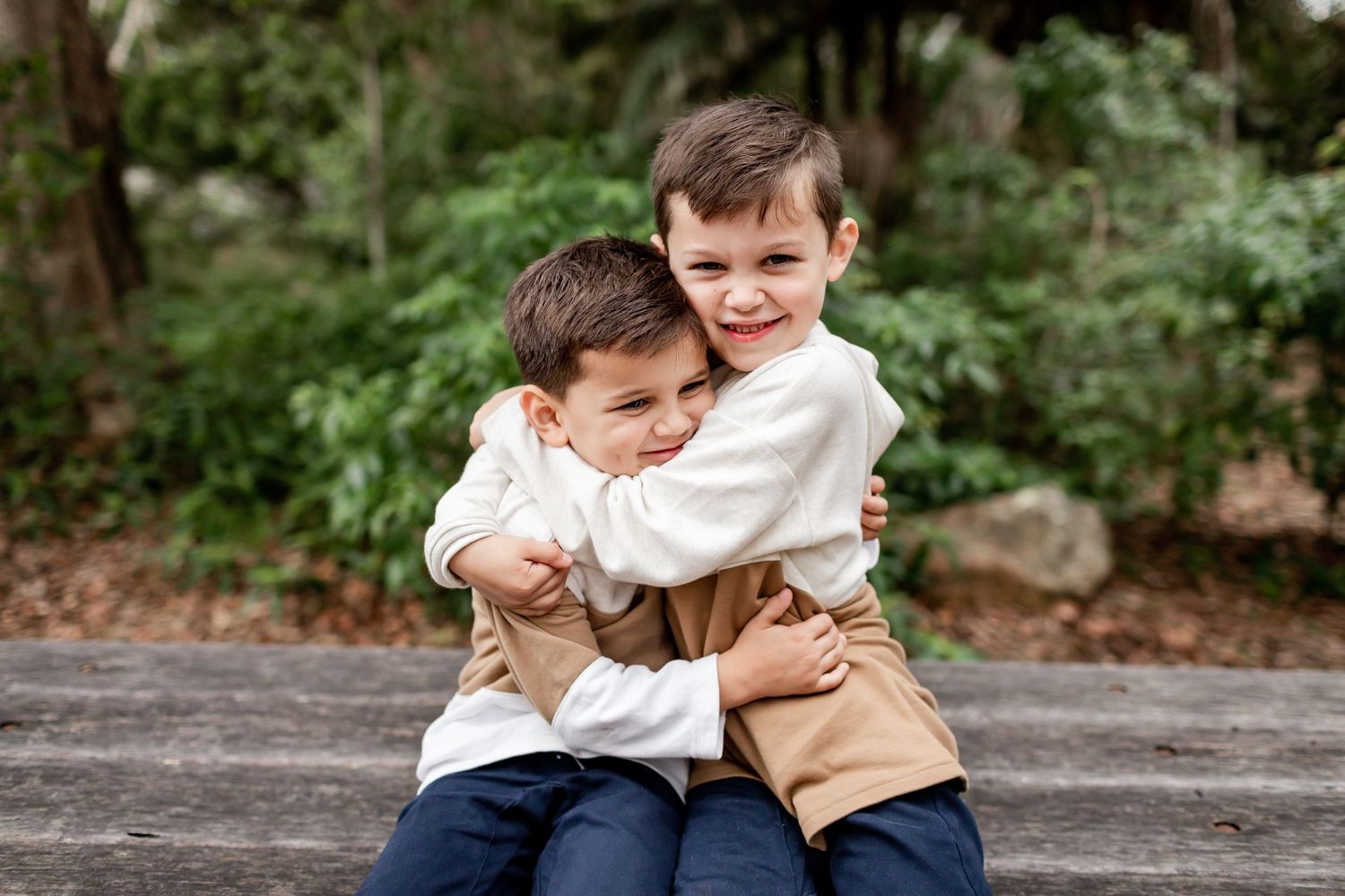 Two children sharing a warm embrace while sitting outdoors.