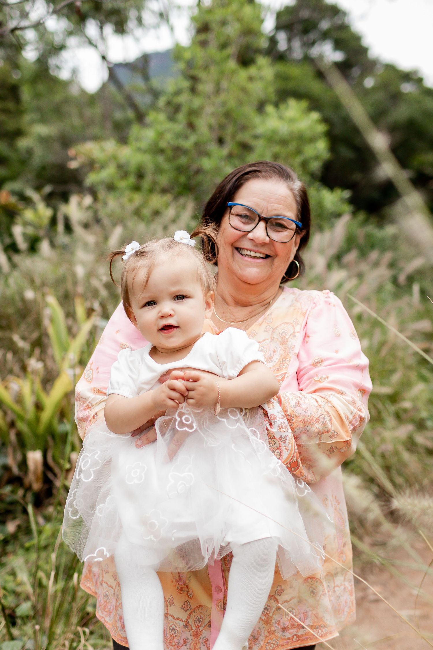 A warm outdoor portrait with a small child wearing white against a natural backdrop.