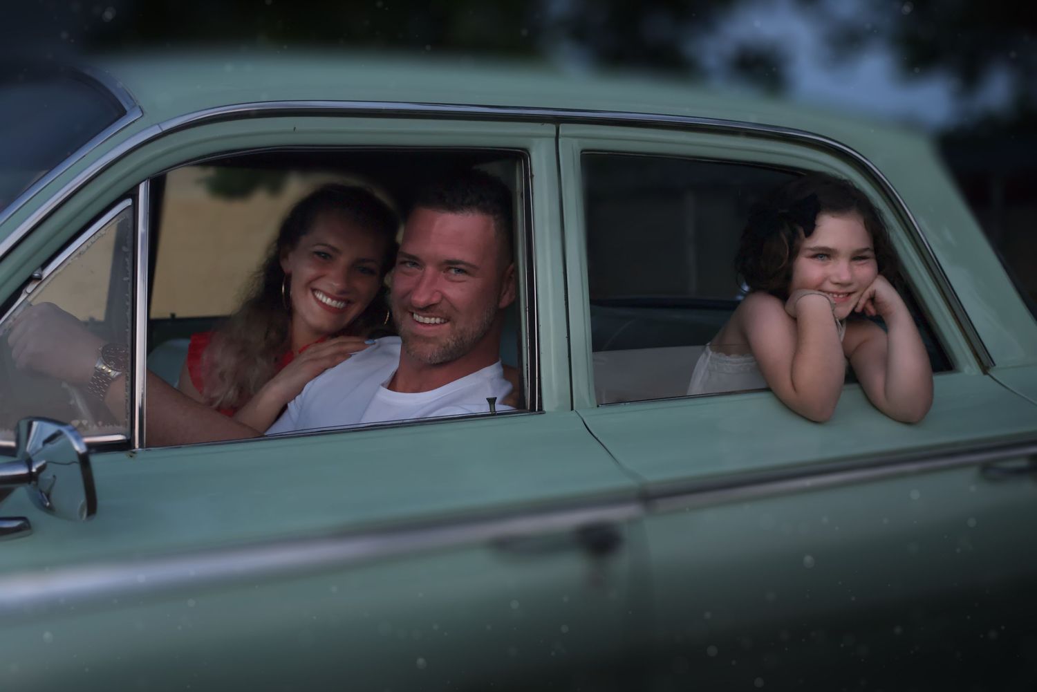 Portrait of husband, wife, and child in classic car.