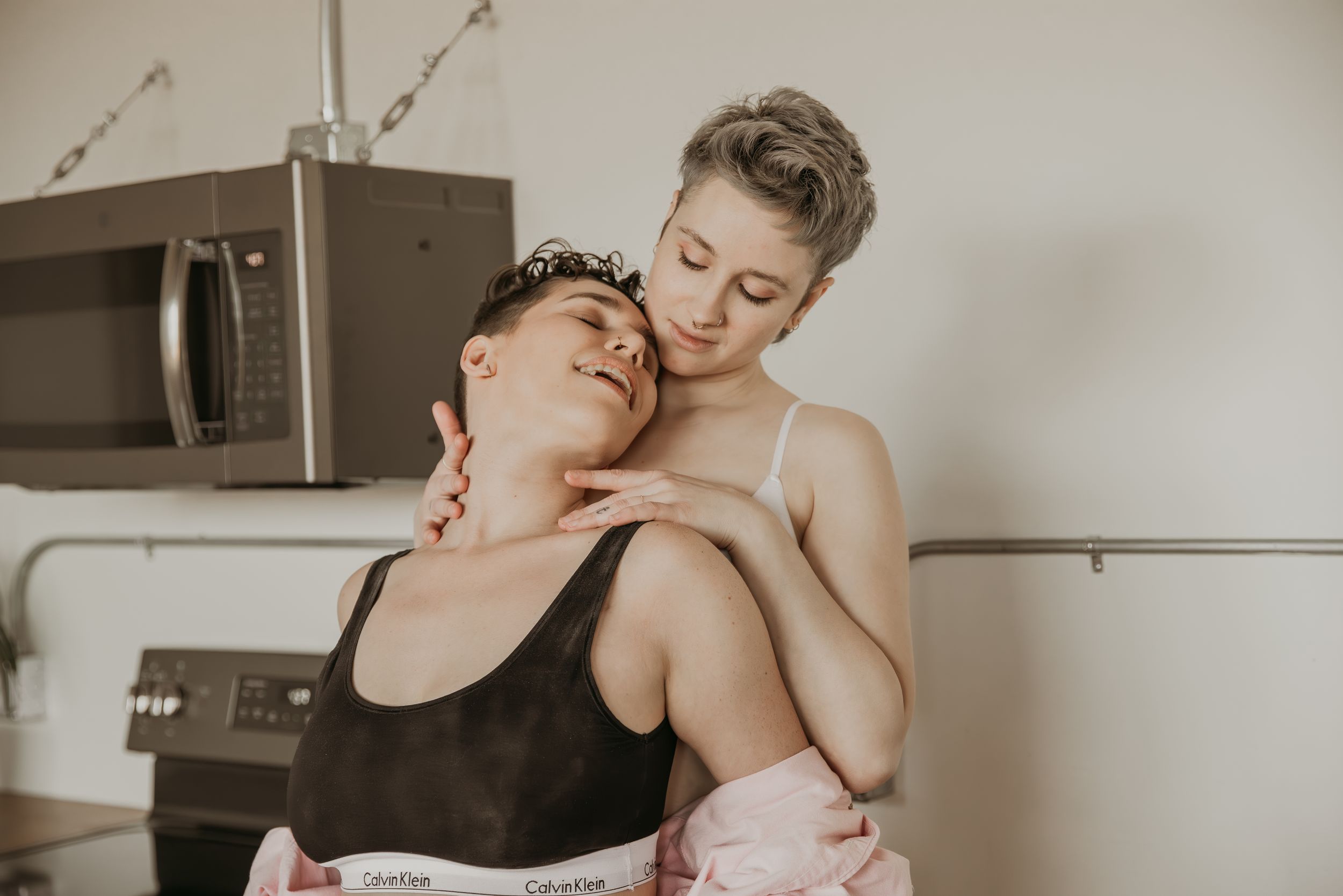 Intimate moment shared between partners in a sunlit kitchen space.