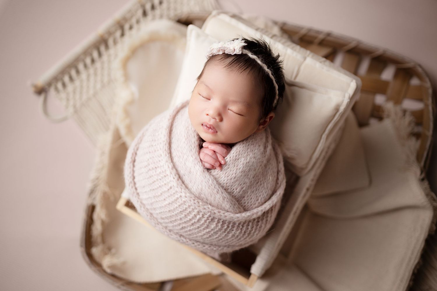 Overhead view of sleeping newborn in soft wrap on vintage furniture.
