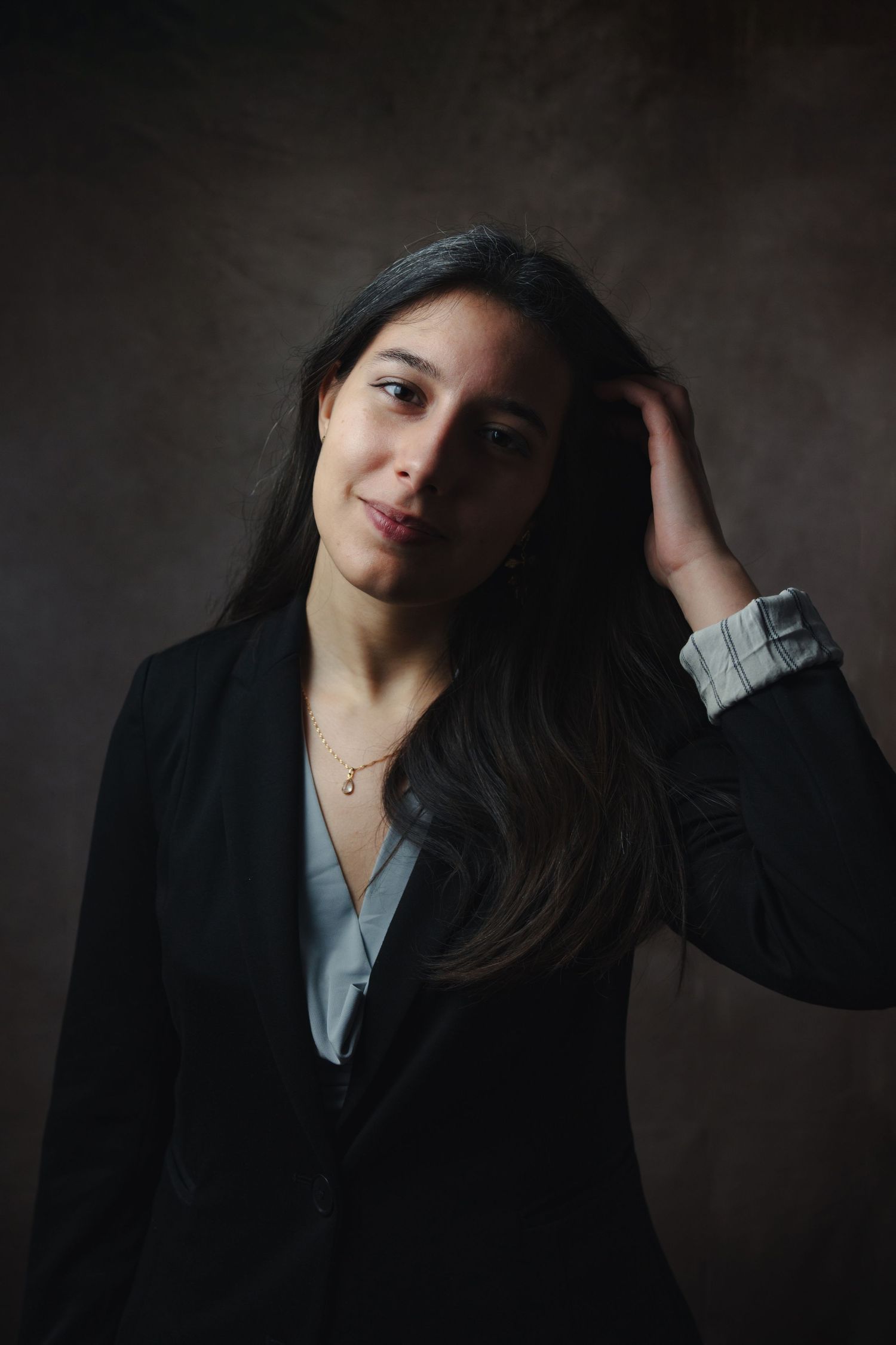 Professional portrait of woman in business attire against dark background.