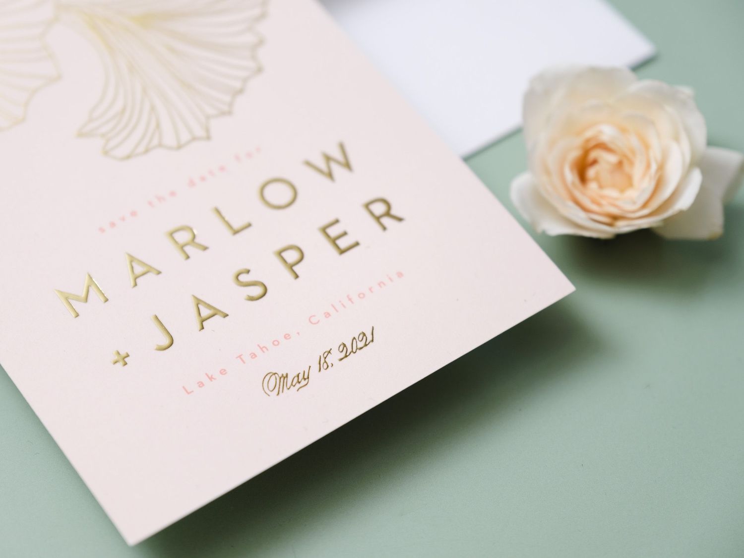 Elegant wedding invitation with gold text reading Marlow and Jasper alongside a delicate peach rose on mint green background.