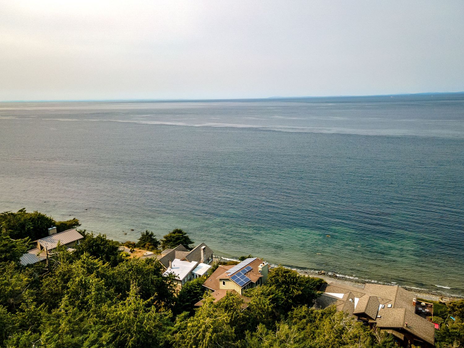 Aerial view of coastal properties with private beach access and turquoise waters.