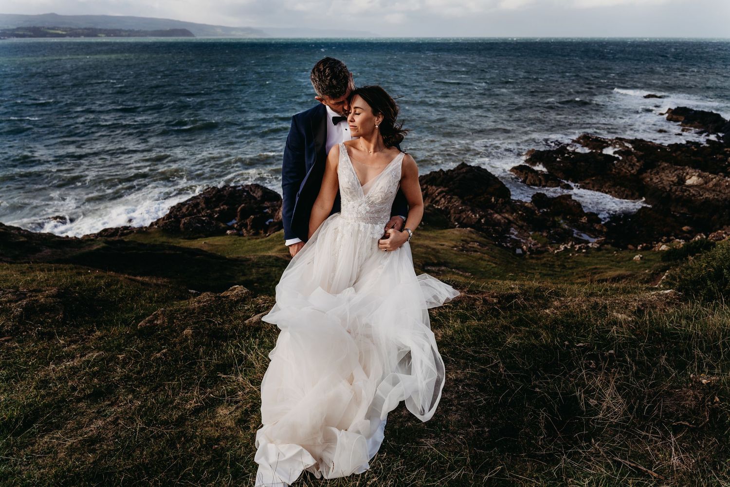 Bride and Groom embracing each other and windswept on their wedding day on the North Coast of Ireland