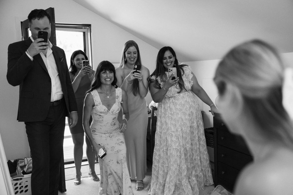 Friends and family laugh as they all take iphone photos of Emery on the morning of her wedding