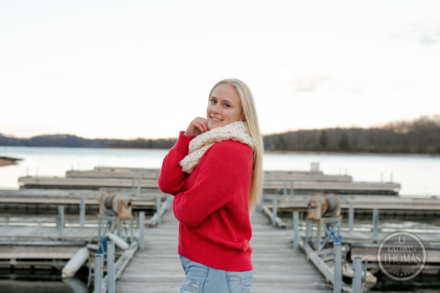 A cozy winter portrait on a lakeside dock with a red sweater against the sunset.
